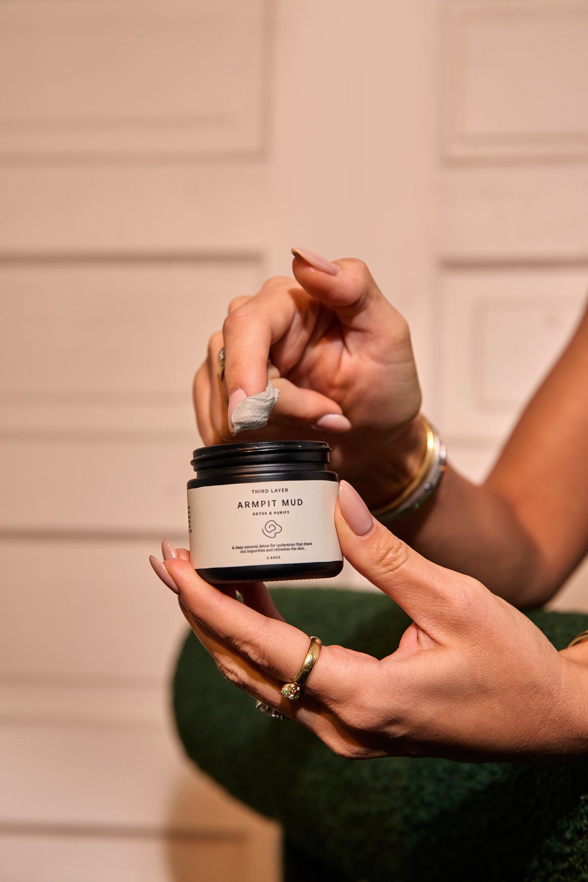 Hands scooping a fingertip of Armpit Mud from the jar